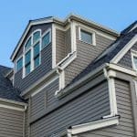 A large, historic home with grey siding in scallop and Dutch lap styles.