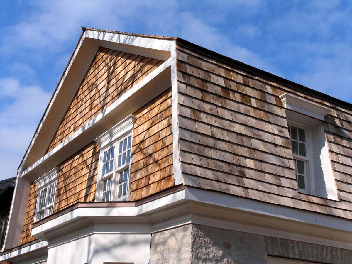 An upward view of a home sided with cedar shakes