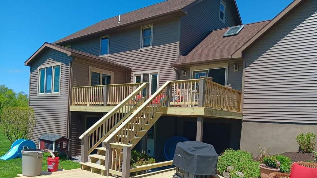 The back of a house with new brown siding and a new deck.