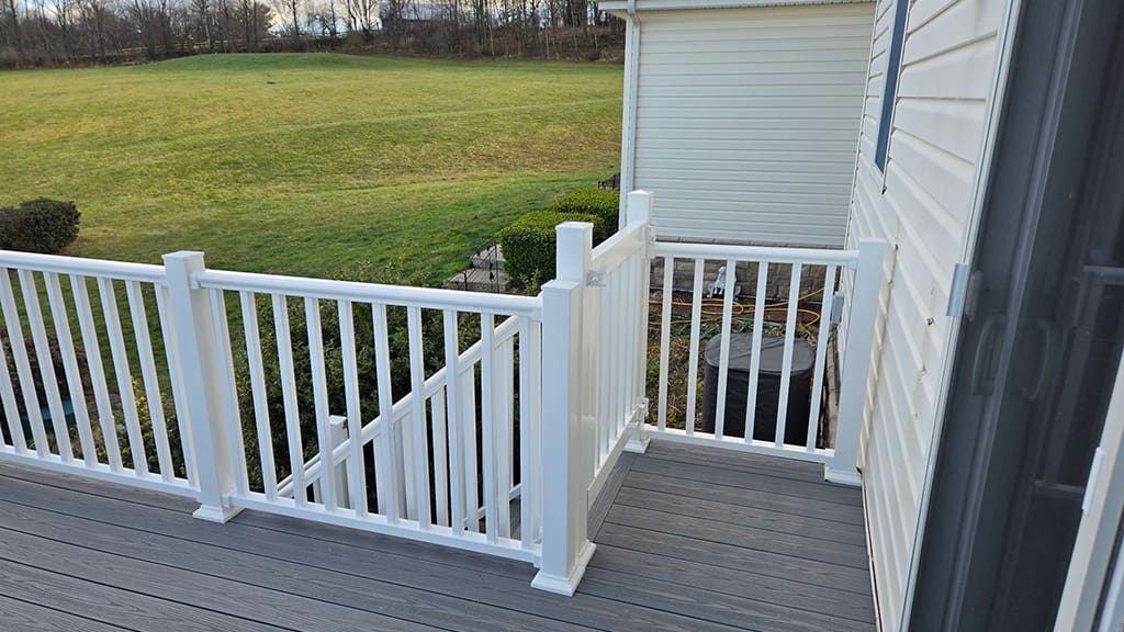 A gray deck with white vinyl railing.