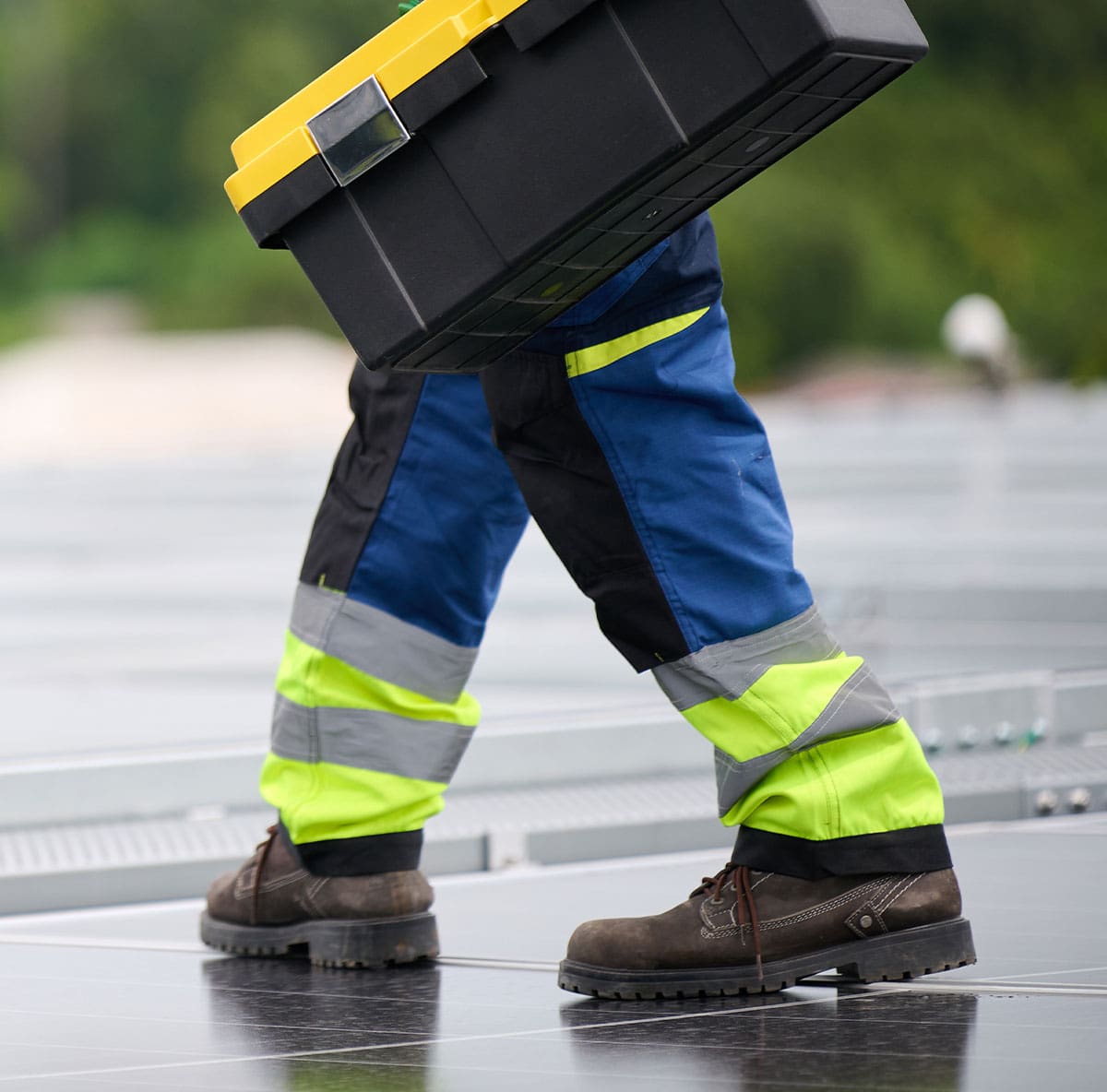 Worker holding a toolbox and inspecting the solar panel on rooftop